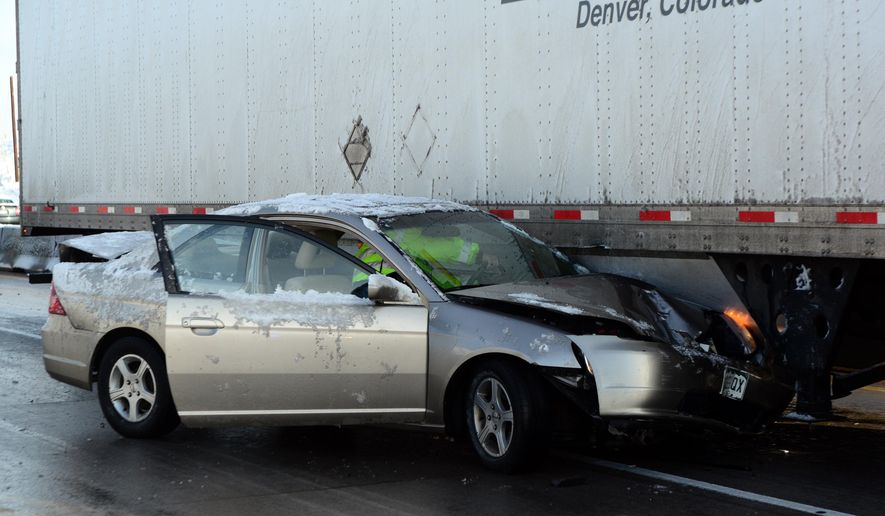 A car is stuck under a semi tractor trailer at the scene of a multi-vehicle pileup on U.S. Highway 36, Friday, April 3, 2015 near Boulder, Colo. Numerous crashes and spin outs on icy and snowy highways have closed portions of several interstates and highways in the Denver and Colorado Springs area as well as the mountains. (AP Photo/The Daily Camera, Paul Aiken) NO SALES