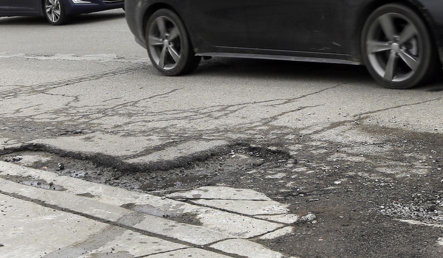 ADVANCE FOR SUNDAY, APRIL 5- Cars drive by a pothole in Detroit, Friday, April 3, 2015. If voters agree to raise taxes for Michigan's deteriorating road and bridge system, 61 cents of every dollar would go to local agencies that say the money could gradually restore roads to respectability within a decade. The large funding increase at the local level, phased in over three years, would include $491 million more to 83 counties and an additional $274 million to more than 500 cities and villages, according to the nonpartisan House Fiscal Agency. (AP Photo/Carlos Osorio)
