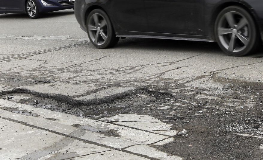 ADVANCE FOR SUNDAY, APRIL 5- Cars drive by a pothole in Detroit, Friday, April 3, 2015. If voters agree to raise taxes for Michigan's deteriorating road and bridge system, 61 cents of every dollar would go to local agencies that say the money could gradually restore roads to respectability within a decade. The large funding increase at the local level, phased in over three years, would include $491 million more to 83 counties and an additional $274 million to more than 500 cities and villages, according to the nonpartisan House Fiscal Agency. (AP Photo/Carlos Osorio)