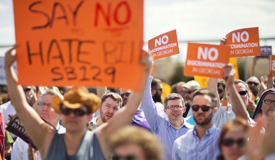 FILE- In this March 17, 2015 file photo, protestors hold up signs during a rally against a contentious "religious freedom" bill in Atlanta. The divide within the Georgia Republican Party on a religious free measure came into clear focus at the March rally opposing the bill. “I will not let a small minority of vocal legislators hijack my state,” David Bachman told the crowd outside the Georgia Capitol. Bachman is a 26-year-old gay man who owns a tie-making company and has been involved with Republican campaigns since high school, personifying the split between his party’s business wing and religious backers. The bill failed to get a House vote on Thursday as lawmakers adjourned for the year. It is likely to return in 2016. (AP Photo/David Goldman, File)