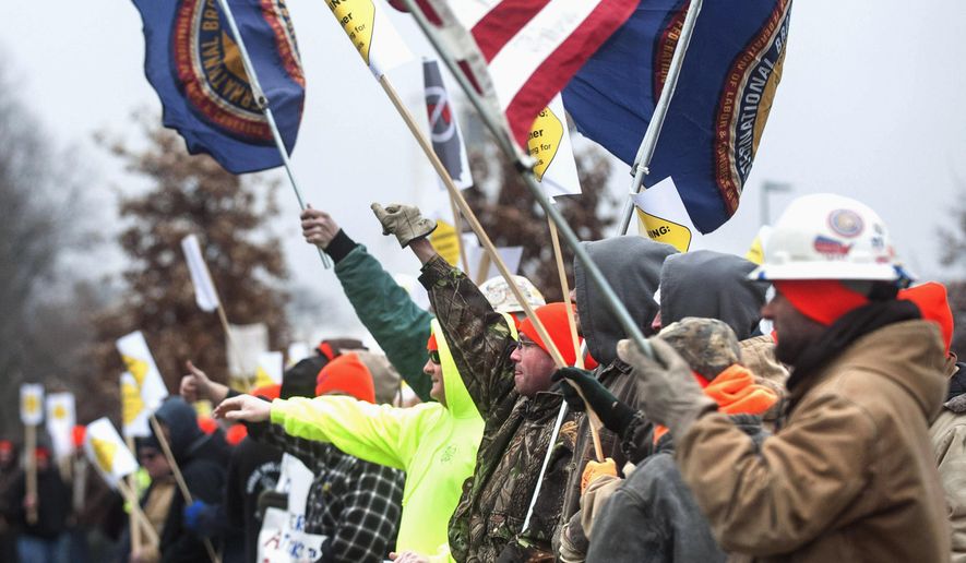 FILE - In this Jan. 29, 2015 file photo, union protesters raise their fists as a passing car honks outside a hotel in Champaign, Ill., where Illinois Gov. Bruce Rauner was speaking to the County Chamber of Commerce. Rauner has made the idea of local right-to-work zones a key piece of his speeches on economic revival since he took office. His ideas have stirred union workers and drawn the attention of outside groups that back right-to-work laws. (AP Photo/The News-Gazette, John Dixon)