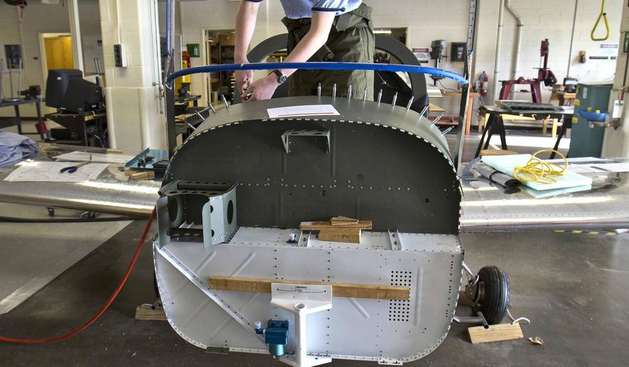 ADVANCE FOR SUNDAY APRIL 5 AND THEREAFTER -This Thursday March 26, 2015 photo shows Denbigh High School senior John Grizzard, 18, as he works on the top of the instrument panel inside the aircraft at the Denbigh High School Aviation Academy in Newport News, Va. Pieces and parts are coming together to look like a real airplane as the Denbigh High School Aviation Academy's RV-12 building project enters its final phases. The two-year project won't be completed this school year as hoped, but it will be completed in the fall semester, said academy director Aaron Smith. (AP Photo/Daily Press, Joe Fudge)