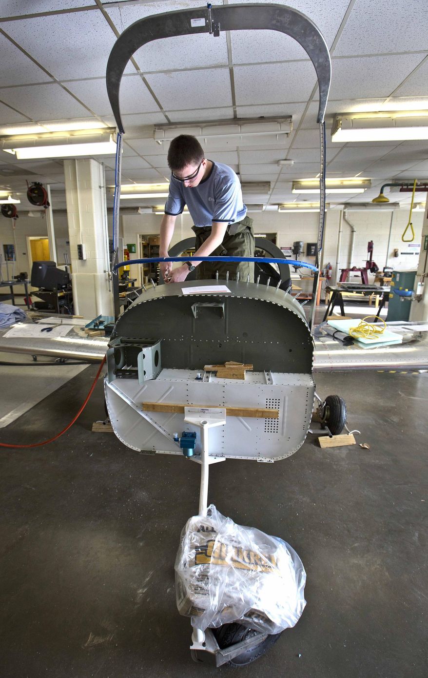 ADVANCE FOR SUNDAY APRIL 5 AND THEREAFTER -This Thursday March 26, 2015 photo shows Denbigh High School senior John Grizzard, 18, as he works on the top of the instrument panel inside the aircraft at the Denbigh High School Aviation Academy in Newport News, Va. Pieces and parts are coming together to look like a real airplane as the Denbigh High School Aviation Academy's RV-12 building project enters its final phases. The two-year project won't be completed this school year as hoped, but it will be completed in the fall semester, said academy director Aaron Smith. (AP Photo/Daily Press, Joe Fudge)