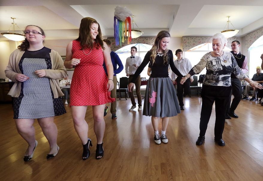 ADVANCE FOR RELEASE SATURDAY, APRIL 4, 2015, AND THEREAFTER- In this March 28, 2015, photo, Sherando High School, Family, Career and Community Leaders of America (FCCLA) members Amelia Powers, left, Olivia Scott, second from left, and Lacey Johnson dance with Hilltop House Assisted Living resident Maria Jordaens during a senior prom in Winchester, Va. The dance, organized by two students from Sherando High School, brought smiles to the faces of many residents and took them back to their school days. (AP Photo/The Winchester Star, Scott Mason)