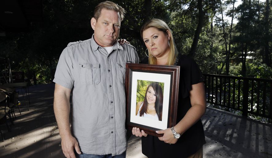 File - In this May 22, 2013 file photo, Larry Pott, left, and his wife Lisa pose for a portrait holding a picture of their daughter Audrie in Saratoga, Calif. Audrie Pott committed suicide in September 2012 after being sexually assaulted by three boys during a house party in Saratoga. (AP Photo/Marcio Jose Sanchez, file)