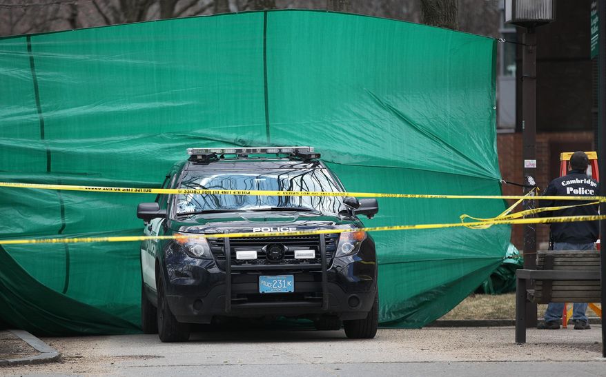 In this April 4, 2015 photo, police stand by where a body was discovered in Cambridge, Mass. Authorities are expected to reveal more details about the weekend discovery of human remains when a suspect appears in court on related charges. (AP Photo/The Boston Globe, Wendy Maeda)