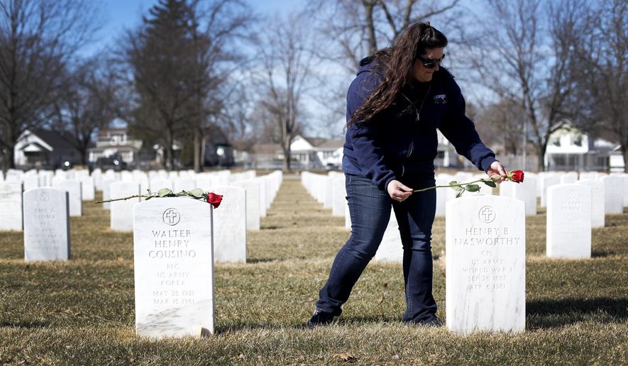 In this March 17, 2015 photo, Paula Kerper places a flower on a headstone at the Ohio Veterans Home cemetery in Sandusky, Ohio. Called Sponsor a Soldier, Kerper plans on placing one red rose at each headstone, about 4,200 in total, within the Ohio Veterans Home cemetery. (AP Photo/The Sandusky Register, Angela Wilhelm)