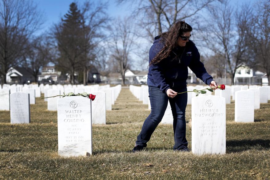 In this March 17, 2015 photo, Paula Kerper places a flower on a headstone at the Ohio Veterans Home cemetery in Sandusky, Ohio. Called Sponsor a Soldier, Kerper plans on placing one red rose at each headstone, about 4,200 in total, within the Ohio Veterans Home cemetery. (AP Photo/The Sandusky Register, Angela Wilhelm)