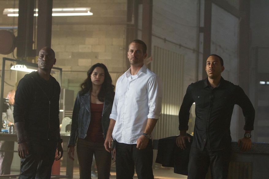 This photo provided by Universal Pictures shows, from left, Tyrese Gibson as Roman, Michelle Rodriguez as Letty, Paul Walker as Brian, and Chris Ludacris as Tej, in a scene from "Furious 7." (AP Photo/Universal Pictures, Scott Garfield)