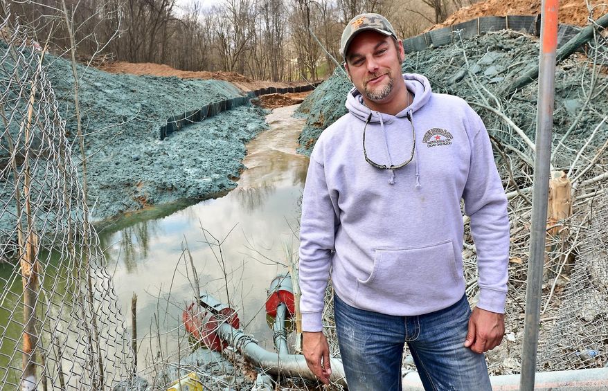 ADVANCE FOR MONDAY APRIL 6 AND THEREAFTER - In this Thursday March 26, 2015 photo, Rodney Loftis stands in front of the creek on Keystone Drive his excavation company diverted after the Yeager Airport land slide. Yeager Airport’s runway extension collapsed in mid-March, sending tons of dirt and rocks onto Keystone Drive and into Elk Twomile Creek in Charleston, W.Va. The landslide destroyed a house and a church. (AP Photo/Charleston Daily Mail, Bob Wojcieszak)