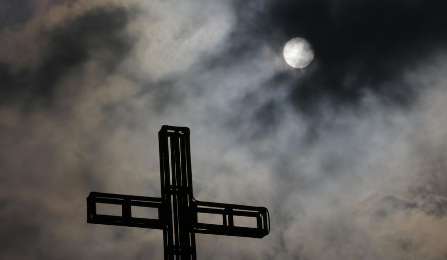 Dark clouds partially cover the sun above a church on Easter Sunday April 5, 2015 in suburban Quezon city, north of Manila, Philippines. Tropical storm Maysak weakened before hitting the Philippines' northeastern coast Sunday, driving away thousands of Lenten holiday vacationers and tourists. (AP Photo/Aaron Favila)