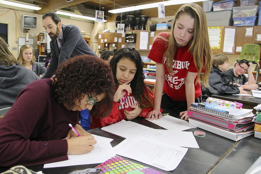 In this March 4, 2015 file photo, Memorial Middle School seventh and eighth grade science teacher Christopher Landry, background, is teaching 8th graders. (AP Photo/Sentinel & Enterprise, John Love) ** FILE **