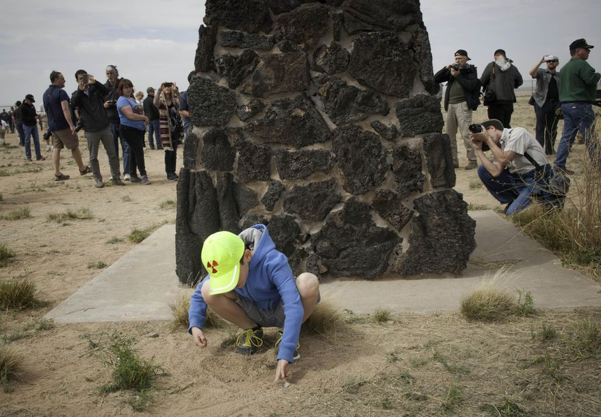 Eight-year-old Josiah Fidel, from Albuquerque, N. M., plays in the dirt next to the obelisk commemorating the first atomic bomb test at the Trinity Site at White Sands Missile Range in New Mexico as other visitors to the site take photographs on April 4, 2015. The White Sands Missile Range opened the Trinity Site to the public for an open house commemorating the 70th anniversary of the first atomic test which took place there on July 16, 1945. Several thousand visitors came to see the site, take photographs and learn more about the event. (AP Photo/Las Cruces Sun-News, Jett Loe)