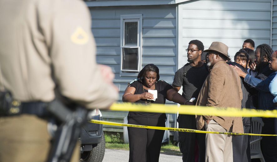 Onlookers gather outside of a house, where police say seven children and one adult have been found dead Monday, April 6, 2015, in Princess Anne, Md. Officers were sent to the home Monday after being contacted by a concerned co-worker of the adult. (AP Photo/The Daily Times, Joe Lamberti)