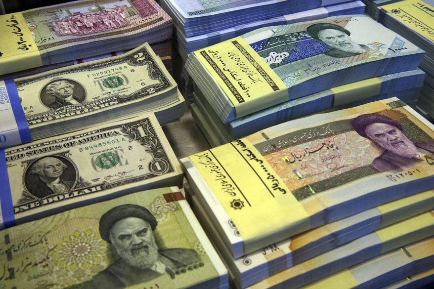In this Saturday, April 4, 2015 photo, Iranian and U.S. banknotes are on display at a currency exchange shop in downtown Tehran, Iran. Should Iran reach a final nuclear accord with world powers that loosens sanctions, the economic opening could give moderates a major boost ahead of crucial parliamentary elections next February. (AP Photo/Vahid Salemi)