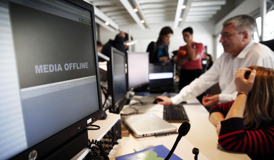 TV5 employees work after the French television network was hacked by people claiming allegiance to the Islamic State group, in Paris, France, Thursday April 9, 2015. The hackers briefly cut transmission of 11 channels belonging to TV5 Monde and took over its websites and social media accounts. (AP Photo/Christophe Ena)