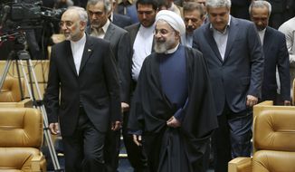 Iranian President Hassan Rouhani (center) arrives to attend a ceremony in Tehran on April 9, 2015, marking National Nuclear Technology Day, as he is accompanied by head of Iran&#39;s Atomic Energy Organization Ali Akbar Salehi (left) and Vice President for Science and Technology Affairs Sorena Sattari (right). (Associated Press) **FILE**