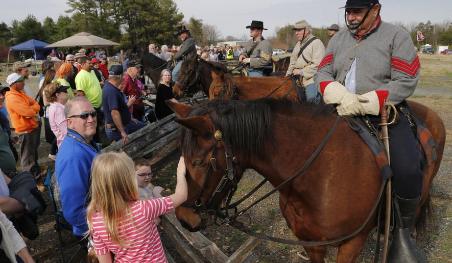 Civil War re-enactor Steve Riggs, of Charleston S.C., with the 2nd Virginia Cavalry, lets visitors pet his horse, Jackson, before a re-enactment of the Battle of Appomattox Station, Wednesday, April 8, 2015, as part of the 150th anniversary of the surrender of the Army of Northern Virginia to Union forces at Appomattox Court House, in Appomattox, Va. (AP Photo/Steve Helber)