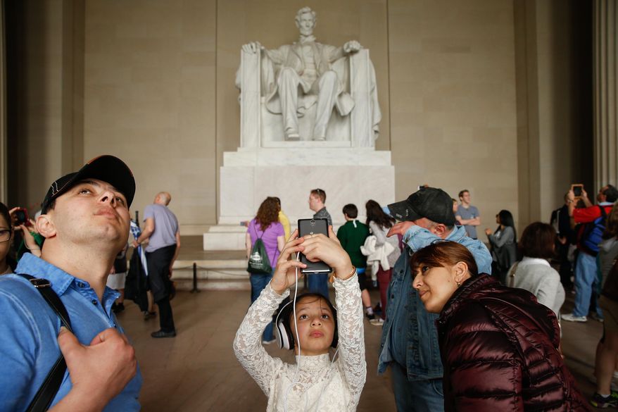 ADVANCE FOR USE SUNDAY, APRIL 12, 2014 AND THEREAFTER - In this Tuesday, April 7, 2015 photo, Asal Amrieva of New York, N.Y., center, takes a photograph while visiting the Lincoln Memorial in Washington. A century and a half after Lincoln was killed, people continue to connect with him in almost personal terms, while searching anew for his relevance to the Republic he left behind. (AP Photo/Andrew Harnik)