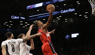 Washington Wizards guard Ramon Sessions (7) goes to the basket past Brooklyn Nets guard Deron Williams (8) and center Brook Lopez during the first half of an NBA basketball game, Friday, April 10, 2015, at  New York.  (AP Photo/Mary Altaffer)