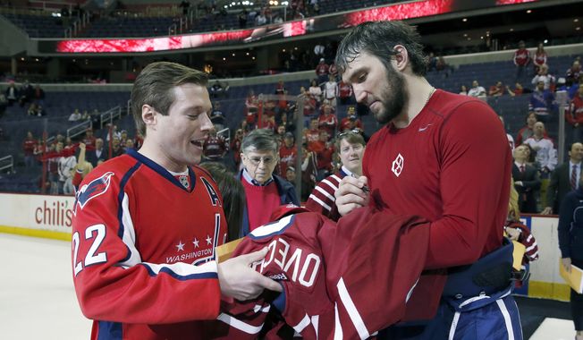 Washington Capitals left wing Alex Ovechkin (8), from Russia, right, signs a jersey he gave to Tom Clinch, from Potomac, Md., during a fan appreciation event after an NHL hockey game against the New York Rangers, Saturday, April 11, 2015, in Washington. The Rangers won 4-2. (AP Photo/Alex Brandon)