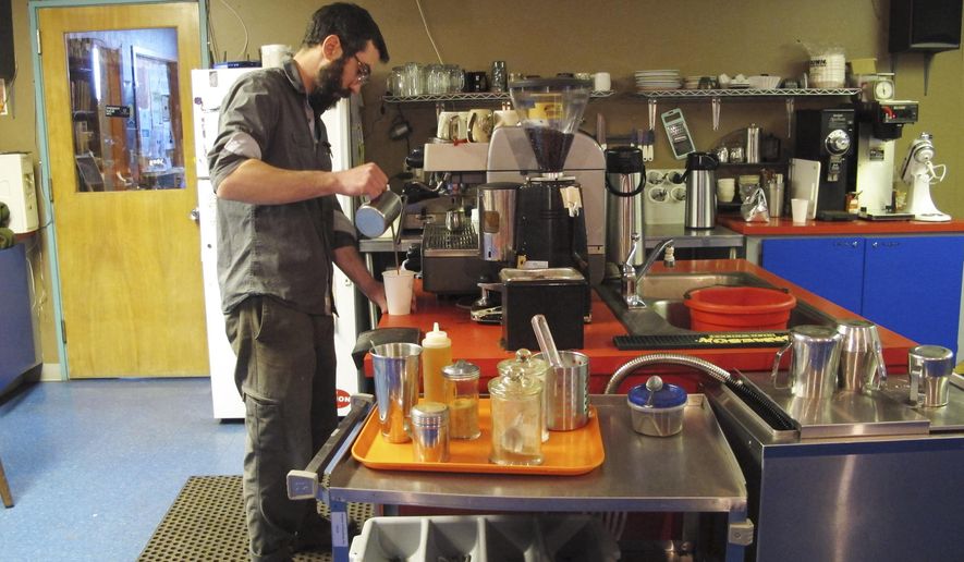 In this April 8, 2015 photo, Joe Curry, a barista and one of the owners at Red Raven Espresso Parlor in Fargo, N.D., serves up a beverage. Curry's shop became the focal point of an anti-discrimination debate after he posted a sign mocking lawmakers who voted against a bill to prohibit discrimination in housing and government based on sexual orientation. (AP Photo/Dave Kolpack)