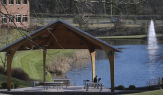 A man sits at a table by an outdoor pavilion next to a pond and fountain at the Virginia Tech Corporate Research Center in Blacksburg, Va.,  Wednesday April 1 2015.  Since 2001, the research and office park has maintained a paid gym on its campus to give both the general public and employees of the many small companies there a recreational outlet during the lunch or after-work hours.(AP Photo / The Roanoke Times, Matt Gentry)