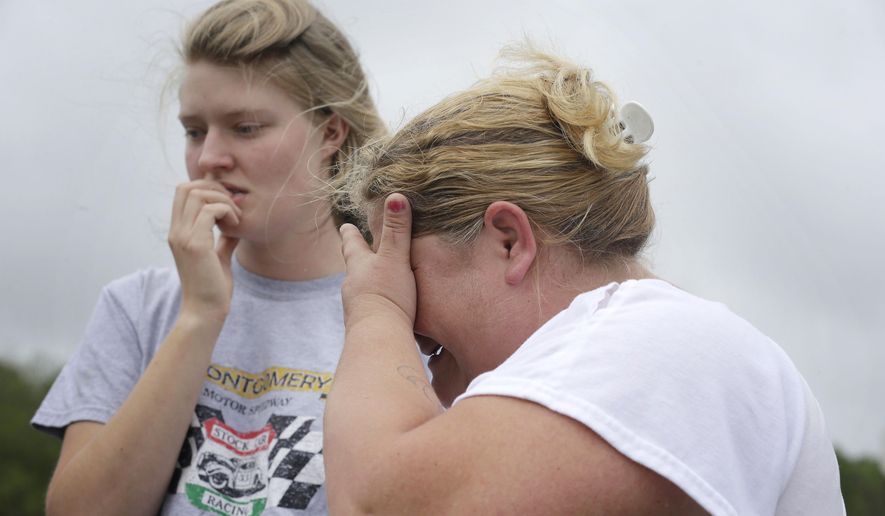 Kristie Brasher, right, cries next to a friend Monday, April 13, 2015, after a gunman entered a doctor's office, shot a woman and fled to a nearby home in Jemison, Ala. (AP Photo/Brynn Anderson)