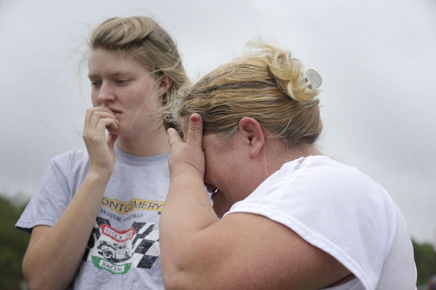 Kristie Brasher, right, cries next to a friend Monday, April 13, 2015, after a gunman entered a doctor's office, shot a woman and fled to a nearby home in Jemison, Ala. (AP Photo/Brynn Anderson)