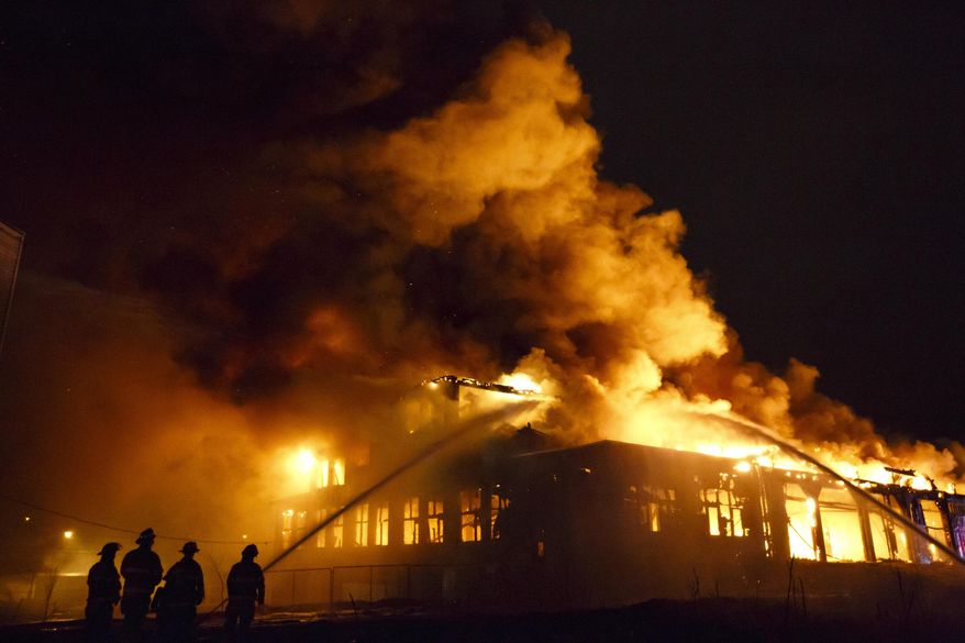 Firefighters work to extinguish a blaze at the vacant Oliver Racing Parts factory near intersection of Cedar Street and Clancy Ave. NE in Grand Rapids, Mich., Sunday, April 12, 2015. Deputy Fire Chief Kevin Sehlmeyer says no one was inside the building at the time, and all firefighters had been accounted for. It's still unclear what caused the fire. (AP Photo/The Grand Rapids Press, Hugh Carey) ALL LOCAL TELEVISION OUT; LOCAL TELEVISION INTERNET OUT