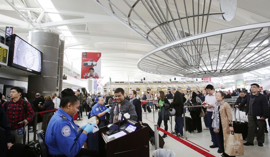In this photo taken Oct. 30, 2014, a TSA officer, left, checks a passenger&#x27;s ticket, boarding pass and passport as part of security screening at John F. Kennedy International Airport in New York. Under legal pressure, the Obama administration will begin telling some suspected terrorists if and why they are on a list of tens of thousands of people banned from flying to, from or within the U.S. (AP Photo/Mark Lennihan)