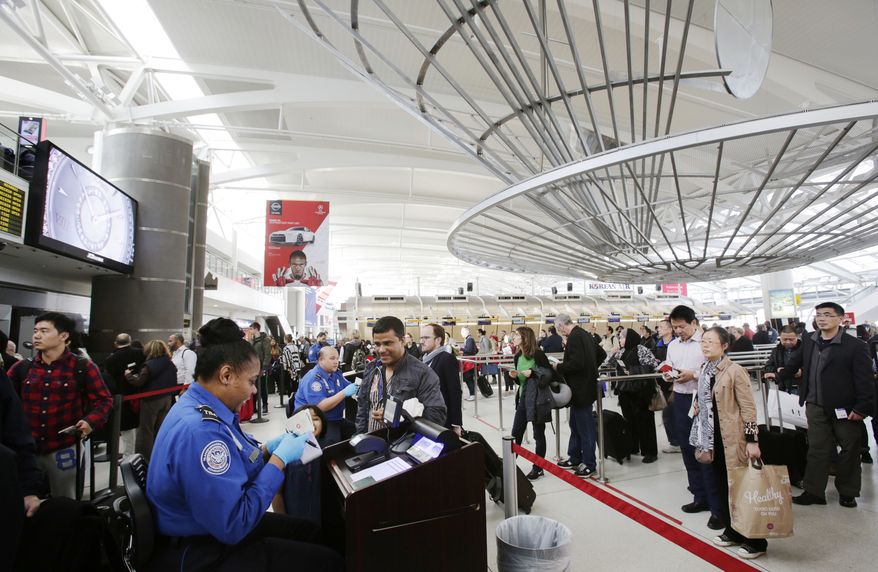 In this photo taken Oct. 30, 2014, a TSA officer, left, checks a passenger's ticket, boarding pass and passport as part of security screening at John F. Kennedy International Airport in New York. Under legal pressure, the Obama administration will begin telling some suspected terrorists if and why they are on a list of tens of thousands of people banned from flying to, from or within the U.S. (AP Photo/Mark Lennihan)
