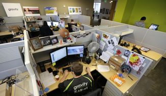 Austin Roos, a support team supervisor, works at lower left, Wednesday, April 15, 2015, at Gravity Payments, a credit card payment processor based in Seattle. Gravity CEO Dan Price told his employees this week that he was cutting his roughly $1 million salary and using company profits so they would each earn a base salary of $70,000, to be phased in over three years. (AP Photo/Ted S. Warren) ** FILE **