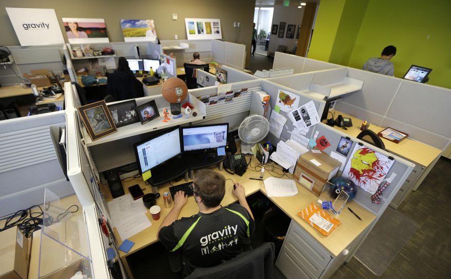 Austin Roos, a support team supervisor, works at lower left, Wednesday, April 15, 2015, at Gravity Payments, a credit card payment processor based in Seattle. Gravity CEO Dan Price told his employees this week that he was cutting his roughly $1 million salary and using company profits so they would each earn a base salary of $70,000, to be phased in over three years. (AP Photo/Ted S. Warren) ** FILE **