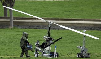 A member of a bomb squad checks a small helicopter after a man landed on the West Lawn of the Capitol in Washington, Wednesday, April 15, 2015. (AP Photo/Manuel Balce Ceneta)