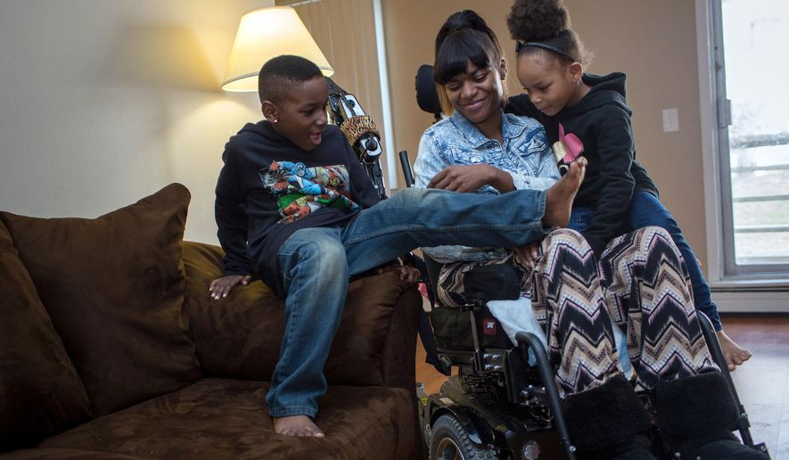 FOR RELEASE MONDAY, APRIL 20, 2015, AT 12:01 A.M. CDT.- Tavaris, left, and Tanaya crawled onto their mother Tanesha Johnson's lap so that the three could watch a movie together Friday, April 10, 2015, in their Brooklyn Center, Minn., apartment. In 2013 Johnson was shot in the neck and paralyzed. After living in a nursing home, she is trying to reunite her family, but struggles to find accessible, affordable housing. (Jennifer Simonson/Minnesota Public Radio via AP)