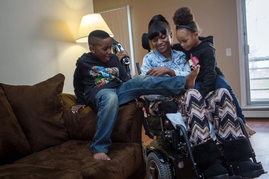 FOR RELEASE MONDAY, APRIL 20, 2015, AT 12:01 A.M. CDT.- Tavaris, left, and Tanaya crawled onto their mother Tanesha Johnson's lap so that the three could watch a movie together Friday, April 10, 2015, in their Brooklyn Center, Minn., apartment. In 2013 Johnson was shot in the neck and paralyzed. After living in a nursing home, she is trying to reunite her family, but struggles to find accessible, affordable housing. (Jennifer Simonson/Minnesota Public Radio via AP)