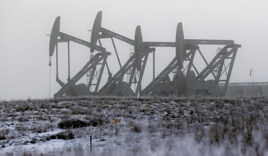 FILE - In this Dec. 19, 2014 file photo, oil pump jacks work in unison on a foggy morning in Williston, N.D. The North Dakota Legislature is looking at restructuring oil taxes as a hedge against falling crude prices. Oil companies could see a big tax cut if crude prices continue to slide, and the state could lose billions of dollars. (AP Photo/Eric Gay, File)