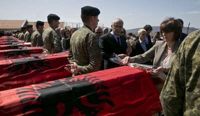Kosovo President Atifete Jahjaga lays flowers on coffins of 21 Kosovo Albanians killed during 1998-99 war with Serbia as they are buried in the village of Cikatove e Vjeter, Kosovo, on Friday, April 17, 2015. (AP Photo/Visar Kryeziu)