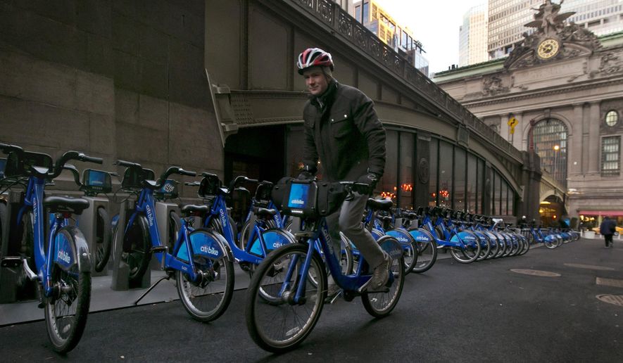 FILE - In this Jan. 13, 2015, file photo, a Citbike cyclist picks up his ride near Grand Central Terminal, background right, in New York. New Yorkers may soon be able to count calories burned and miles traveled while pedaling Citi Bikes, the popular bicycle-sharing program with a troubled history that is undergoing a major overhaul under new leadership. (AP Photo/Richard Drew, File)