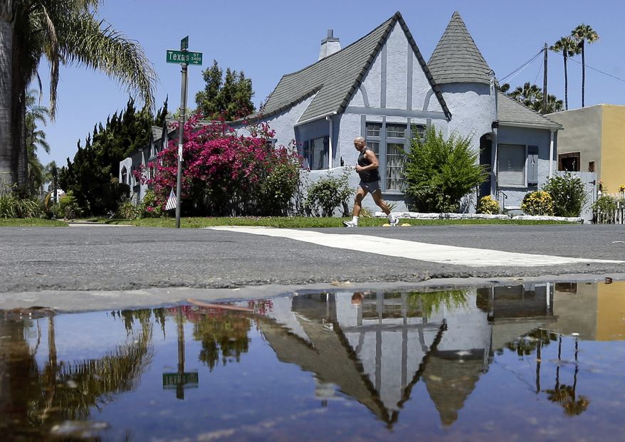 A house is reflected in a puddle of water from an irrigated front yard in San Diego. State regulators on Saturday, April 18, 2015  announced a revised plan to reduce water use in drought-stricken California that offers easier conservation targets for major cities, including Los Angeles, while demanding greater cutbacks from others. The new water reduction targets released by the State Water Resources Control Board responds to criticisms from cities that said earlier targets were unrealistic and unfair. Recognizing that some communities are farther along than others in conservation, the water board released a draft plan last week that requires varying levels of cutbacks for cities to ensure enough water if dry conditions persist. (AP Photo/Gregory Bull, File)