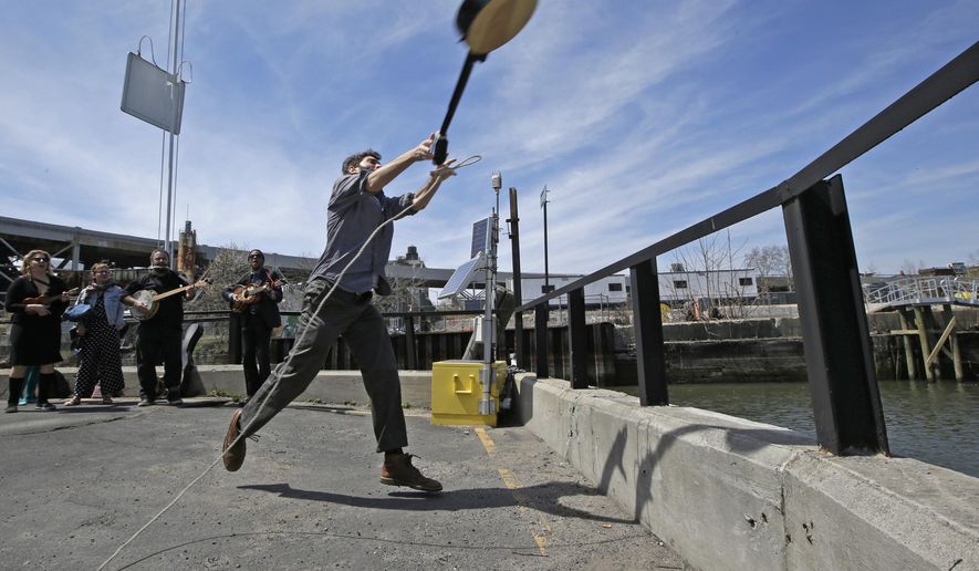 Event founder, banjo player and folk music promoter Eli Smith tosses a banjo during the fifth annual Brooklyn Folk Festival's Gowanus Banjo Toss, Sunday, April 19, 2015, in the Brooklyn borough of New York. About two dozen people participated in the annual event. Smith who conceived the event said, "I love the banjo, but sometimes I have the perverse desire to see it thrown into a body of water." (AP Photo/Kathy Willens)