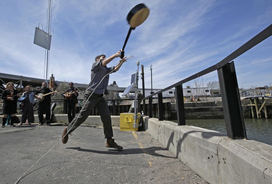 Event founder, banjo player and folk music promoter Eli Smith tosses a banjo during the fifth annual Brooklyn Folk Festival's Gowanus Banjo Toss, Sunday, April 19, 2015, in the Brooklyn borough of New York. About two dozen people participated in the annual event. Smith who conceived the event said, "I love the banjo, but sometimes I have the perverse desire to see it thrown into a body of water." (AP Photo/Kathy Willens)