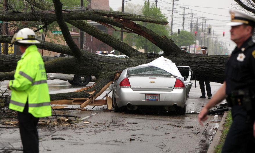 Police investigate after a car was crushed by a tree killing the driver Sunday, April 19, 2015 in Cincinnati. (Cameron Knight/The Cincinnati Enquirer via AP) MANDATORY CREDIT; NO SALES