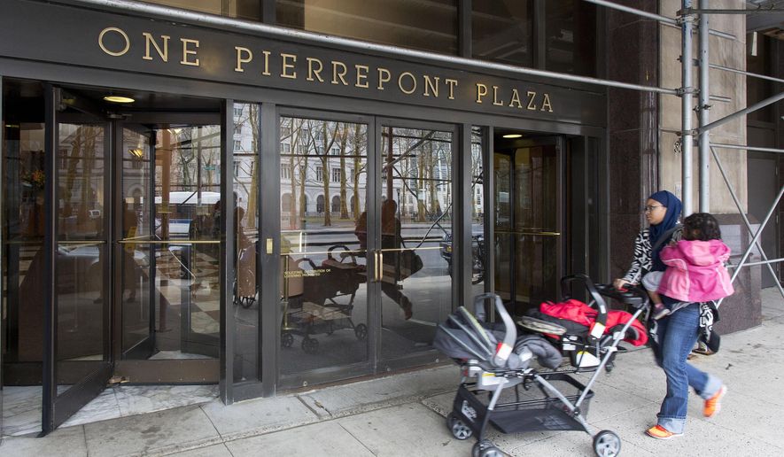 FILE- In this April 3, 2015 file photo, a woman enters One Pierrepont Plaza in the Brooklyn borough of New York. The 19-story office building rises unassumingly from downtown Brooklyn, its upper floors offering generous views of the nearby Manhattan skyline and the East River’s famed bridges. Inside, the headquarters of what will arguably be the most scrutinized presidential campaign in history, Hillary Clinton’s second bid at the White House. (AP Photo/Mark Lennihan, File)