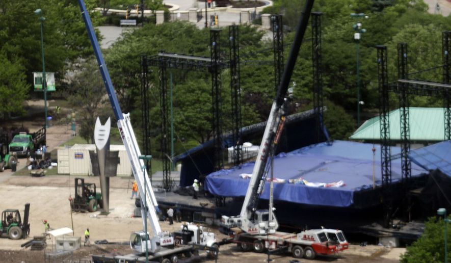 Construction workers take down a stage in Centennial Olympic Park after patrons attending a festival turned the grass to mud during a rain storm, Monday, April 20, 2015, in Atlanta. Park officials couldn't immediately be reached, but a recorded message states that the park would be closed Monday for cleanup after the SweetWater 420 Fest. (AP Photo/Mike Stewart)