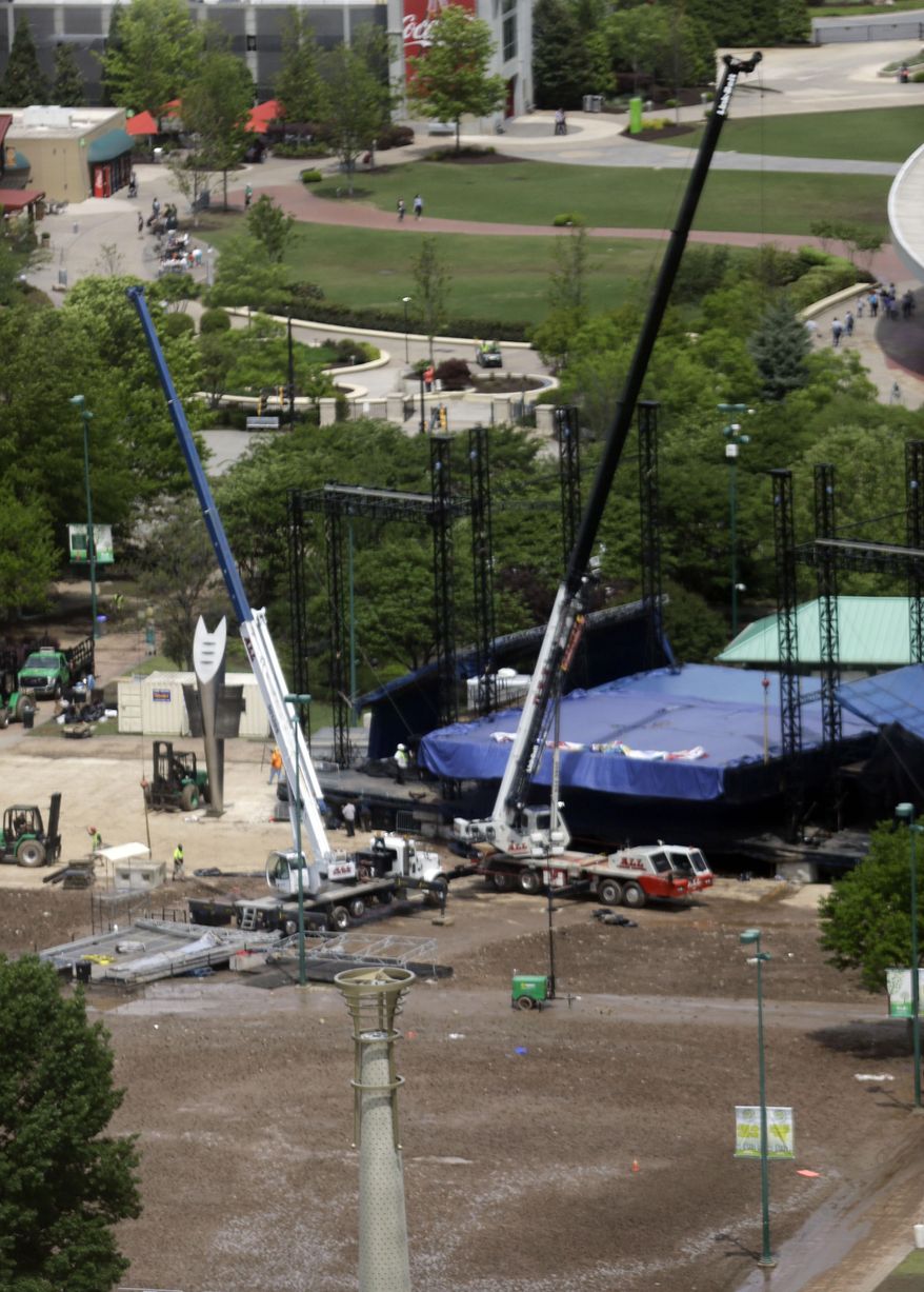 Construction workers take down a stage in Centennial Olympic Park after patrons attending a festival turned the grass to mud during a rain storm, Monday, April 20, 2015, in Atlanta. Park officials couldn't immediately be reached, but a recorded message states that the park would be closed Monday for cleanup after the SweetWater 420 Fest. (AP Photo/Mike Stewart)