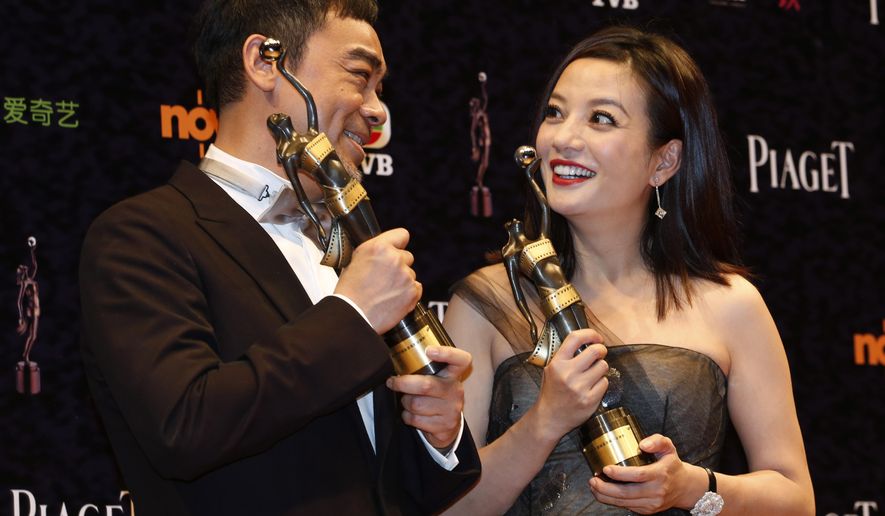 Hong Kong actor Sean Lau, left, poses with his Best Actor award for the movie “Overhead 3” alongside Chinese actress Zhou Wei with her Best Actress award for the movie “Dearest” during the Hong Kong Film Awards in Hong Kong Sunday, April 19, 2015. (AP Photo/Kin Cheung)