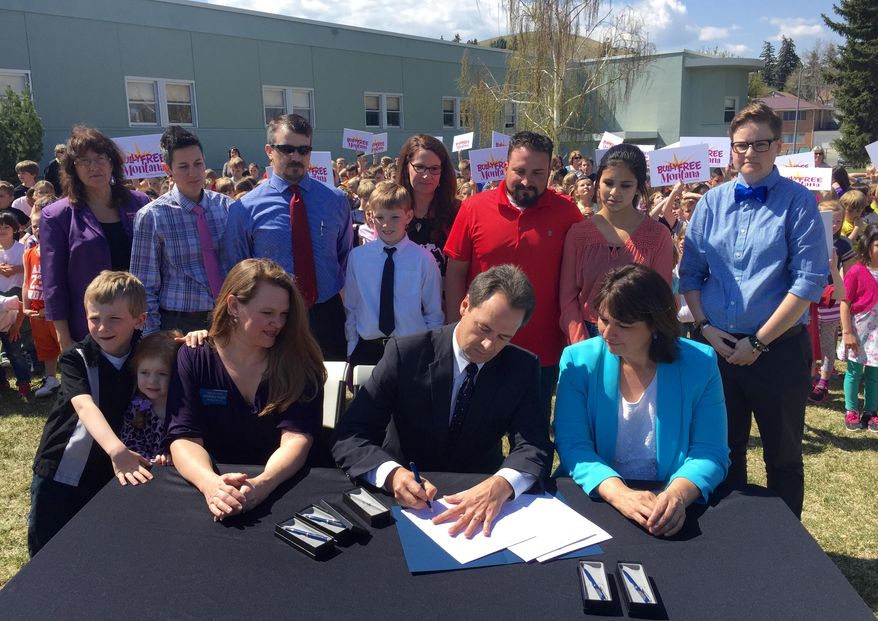 Montana Gov. Steve Bullock signs the Bully Free Montana Act Tuesday, April 21, 2015 at Jefferson Elementary in Helena, Mont., while bill sponsor Rep. Kim Dudik, left, and Superintendent of Public Instruction Denise Juneau look on. Lawmakers have been trying to pass some form of the measure since 2003 with opponents saying it would infringe on school districts' ability to enact local rules. Forty-six of the 49 states that have established bullying laws did so by 2010. (AP Photo/Lisa Baumann)