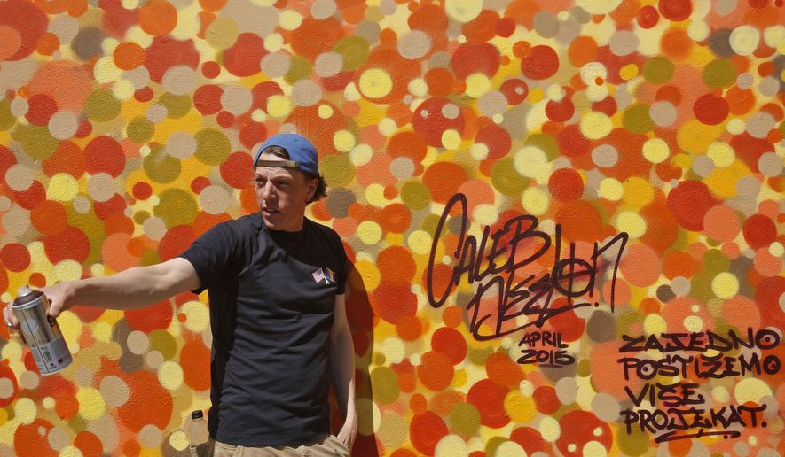 American graffiti artists Caleb Neelon poses for photo in front over work on a wall in Bosnian capital of Sarajevo, on Tuesday, April, 21.2015. American graffiti artists Caleb Neelon, the author of street murals in numerous cities around the world, has gathered youths from different sides of Bosnia’s ethnic divide to jointly work on a peace-promoting project. (AP Photo/Amel Emric)